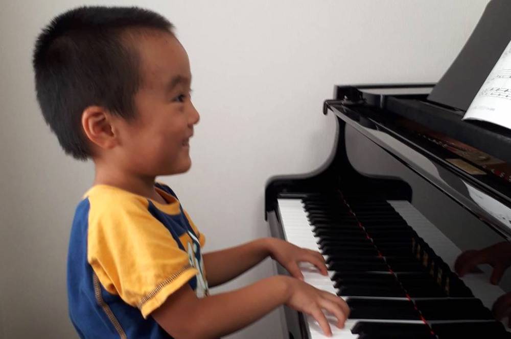 男児の生徒さんが楽しそうにピアノを弾く写真